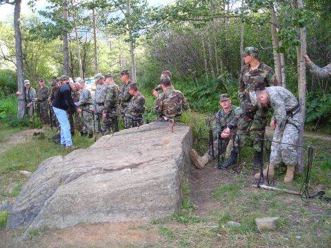 2003 Jeep TJ - A group of soldiers are assembled in a wooded area, with some interacting near a large rock formation.