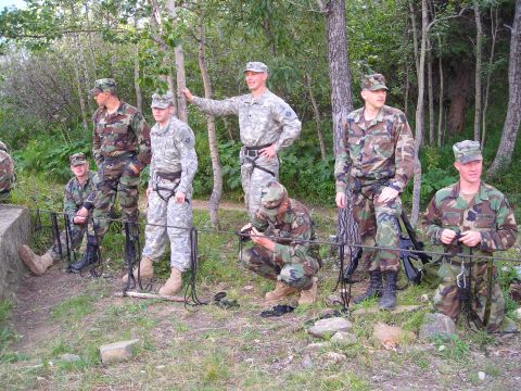 2003 Jeep TJ - Soldiers in camouflage uniforms prepare for an outdoor activity, with climbing gear visible.