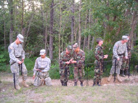 2003 Jeep TJ - Military personnel train with ropes and harnesses in a forest setting, preparing for rappelling exercises.