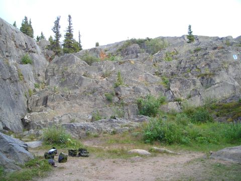 2003 Jeep TJ - A natural scene of a rocky hillside with sparse vegetation and trees under an overcast sky.