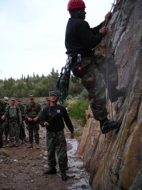 2003 Jeep TJ - A group of soldiers observe a climber ascending a rocky cliff during a training exercise.