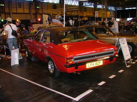2001 Ford Fiesta - A red sedan with a black vinyl roof is displayed indoors, with another car visible to the right.
