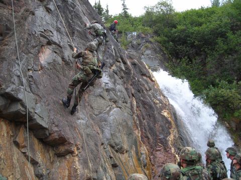 2003 Jeep TJ - Military personnel practice rappelling down a steep, rocky cliff face with a waterfall cascading nearby.