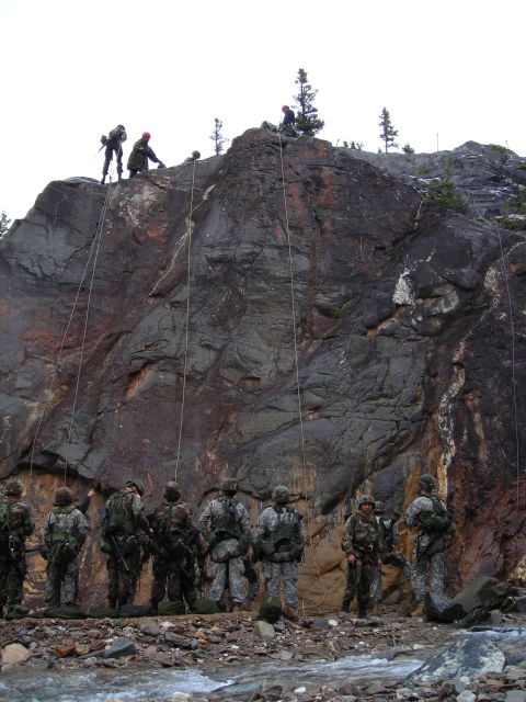 2003 Jeep TJ - Military personnel practice rappelling down a steep, rocky incline, with a stream flowing at the base of the cliff.