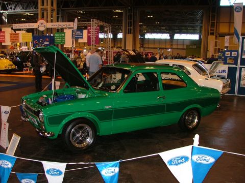 2001 Ford Fiesta - Green classic Ford Escort Mk1 at a car show, hood open. Another vehicle is parked behind it.
