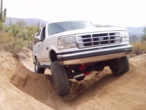 1993 Ford Bronco - A white 1992 Ford Bronco navigates a steep dirt incline in a desert landscape.