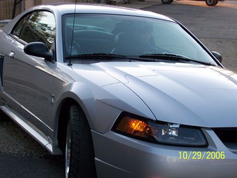 1998 Ford Taurus - This silver coupe is shown from the front quarter angle, with a driver visible inside.