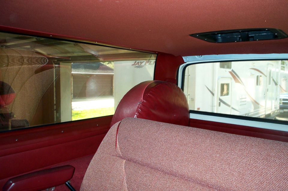 Interior view of a vehicle showing red seats and a red spare tire cover. Text 'SUPERMOTORS' visible