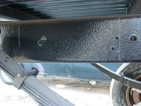 1979 Ford Bronco - Underside view of a vehicle's frame and suspension components, showing the textured black paint and leaf springs.
