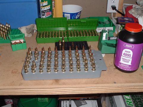 1995 Mercury Grand Marquis - Reloading supplies including bullets, ammo boxes, and smokeless powder are laid out on a workbench.
