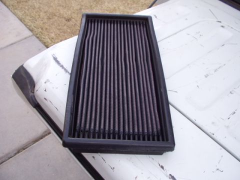 1993 Ford Bronco - A K&N air filter rests on the hood of a vehicle, which shows signs of wear and tear.