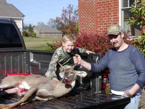 1988 Ford Bronco - A man and child pose with a deer in the back of a pickup truck after a hunt.