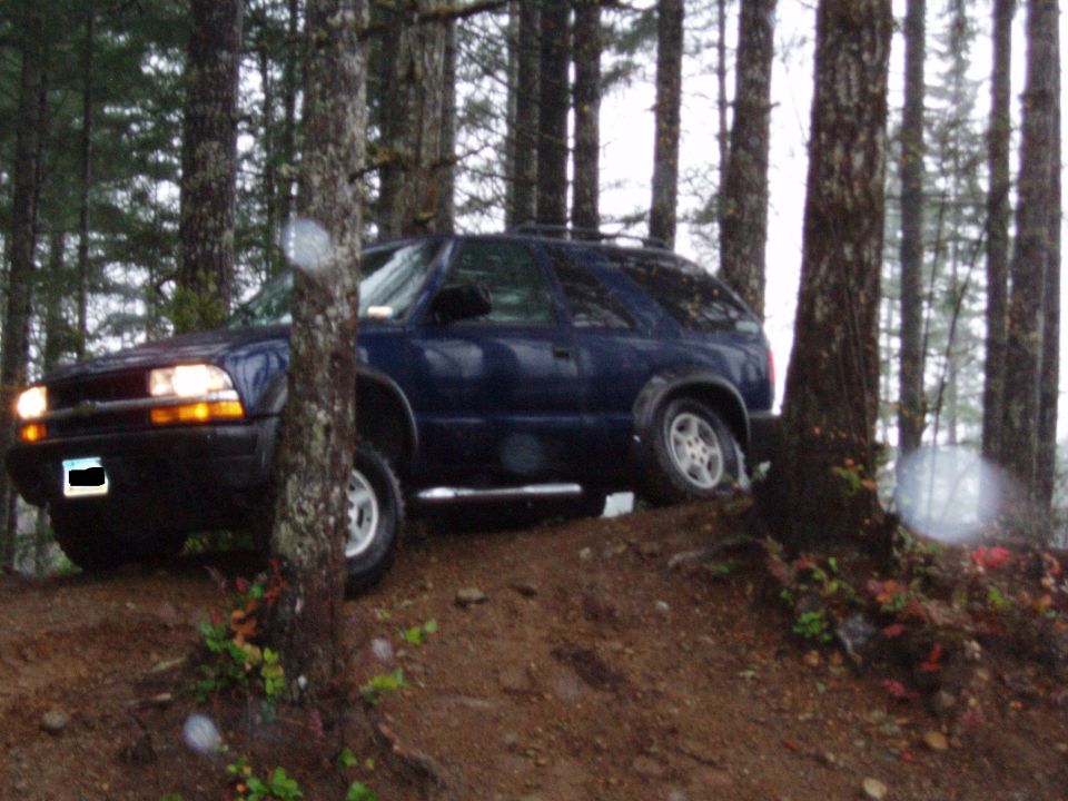 Blue SUV driving on a dirt road in a forest