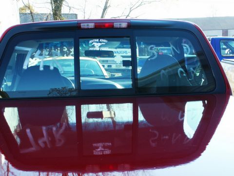 2001 Mercury Grand Marquis - Reflection in the rear window of a red pickup truck shows another vehicle and a sign with text.