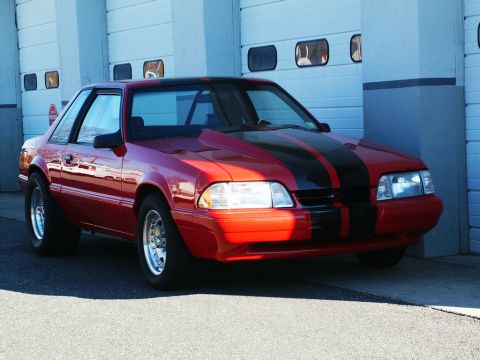 2001 Mercury Grand Marquis - This red coupe with black racing stripes is parked in front of a garage with a modified hood.