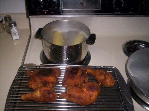1989 Ford Bronco - Fried chicken rests on a cooling rack next to a pot of boiling water on a stovetop.