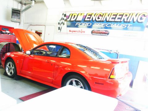 2001 Mercury Grand Marquis - A red Ford Mustang is positioned on a dynamometer inside a garage with the hood open.