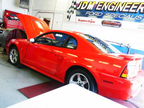 2001 Mercury Grand Marquis - A red 2001 Ford Mustang is positioned on a dynamometer with its hood open inside a garage.