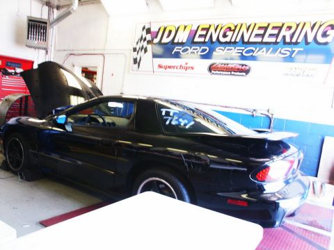 2001 Mercury Grand Marquis - A black Pontiac Firebird is positioned on a dynamometer inside a garage with the hood up.