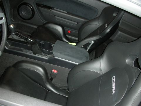 1998 Ford Crown Victoria - Black leather sport seats embroidered Cobra flank a center console inside a two-door coupe.