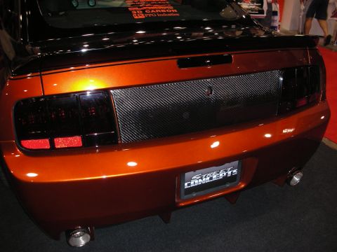 1998 Ford Crown Victoria - rear of a copper-orange Mustang shows smoked taillights, a carbon-fiber center panel and dual exhaust tips.