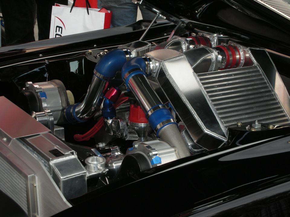 Highly polished twin-turbo engine bay with blue and red hoses and a large intercooler