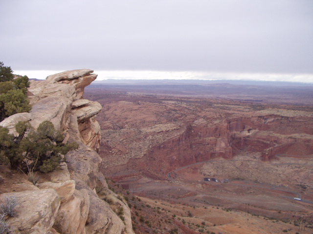 Rocky outcrop overlooking a red-rock canyon under a cloudy sky