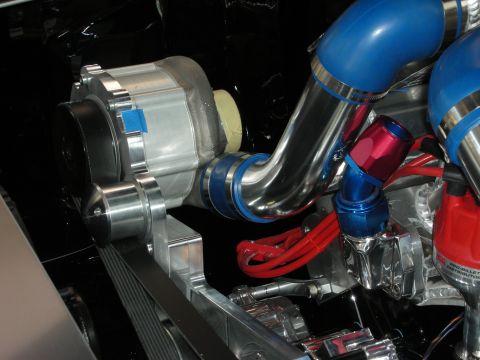 1998 Ford Crown Victoria - chrome alternator and polished pulley sit beside a blue intake pipe and red braided hoses in a detailed engine bay.