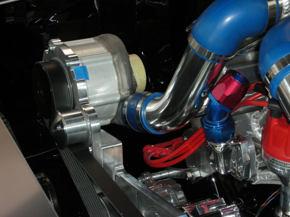 Chrome alternator and polished pulley with blue intake pipe and red braided hoses in engine bay