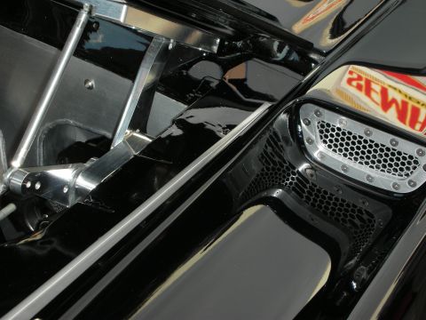 1998 Ford Crown Victoria - glossy black fender and engine-bay corner features a mesh side vent and a polished tubular bracket.