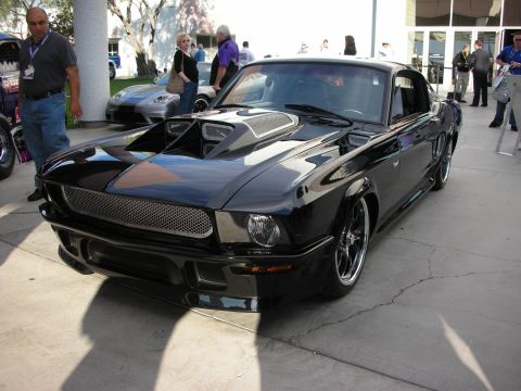 1998 Ford Crown Victoria - Lowered black custom fastback with twin hood scoops, dark mesh grille, and multi-spoke chrome wheels parked on pavement among show spectato…