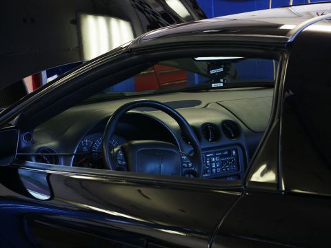2001 Mercury Grand Marquis - Interior view of a black Pontiac Firebird, showing the dashboard and steering wheel.