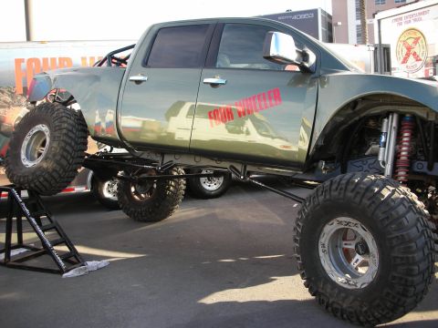 1998 Ford Crown Victoria - Lifted crew-cab show pickup lettered 'Four Wheeler' with a tube cage, long-travel suspension, coilover shocks, and oversized mud tires.