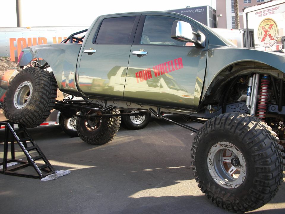 Lifted crew-cab pickup with Four Wheeler graphics and large mud tires