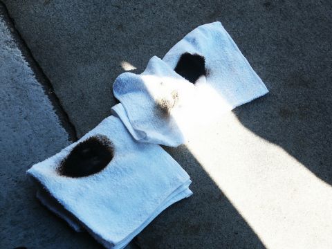 2001 Mercury Grand Marquis - Towels stained with oil lie on a concrete surface, illuminated by sunlight.