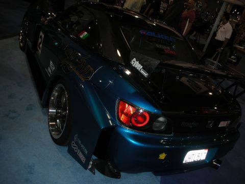 1998 Ford Crown Victoria - teal wide-body Honda S2000 race car shows its halo-ring taillight and aero kit on a carpeted indoor display.