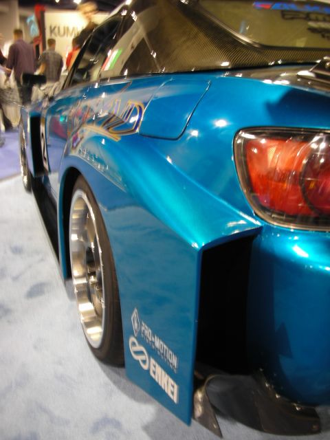 1998 Ford Crown Victoria - rear quarter of a blue wide-body Honda S2000 shows an Enkei wheel, mud flap and carbon diffuser on a show floor.