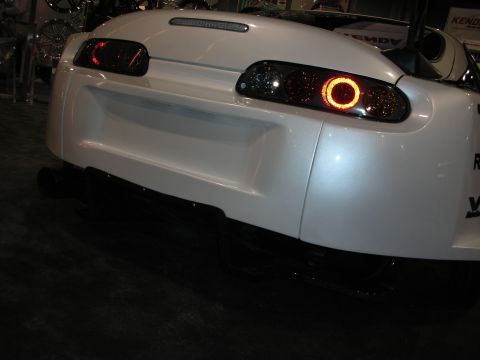 1998 Ford Crown Victoria - Rear view of a white Toyota Supra showing illuminated halo-ring taillights and rear bumper under show lighting.