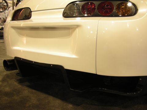1998 Ford Crown Victoria - Close-up of a white Toyota Supra's rear bumper, exhaust tip, and black diffuser with multiple taillights.