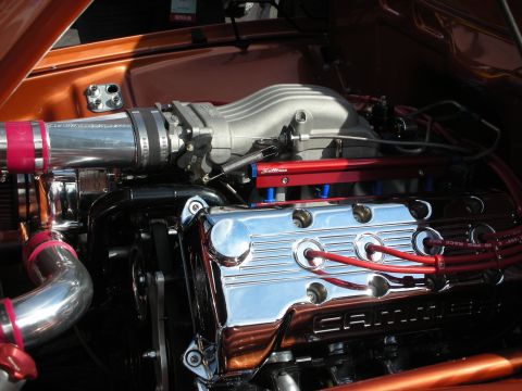 1998 Ford Crown Victoria - Close-up of a polished engine with chrome valve covers, red plug wires, and intake tubing in a copper-colored engine bay.