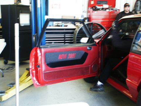 2001 Mercury Grand Marquis - Interior view of a red car with racing modifications, including a roll cage and custom door panel.