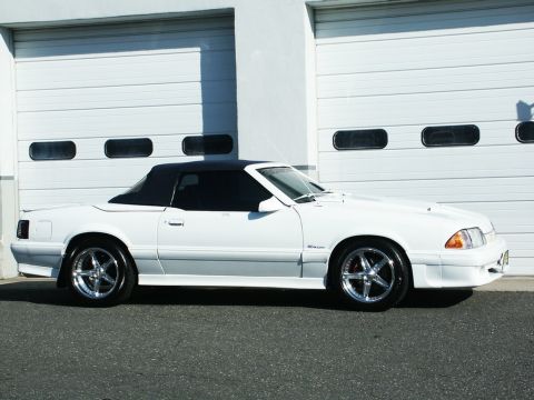 2001 Mercury Grand Marquis - A white convertible with chrome wheels is parked in front of a white garage door.