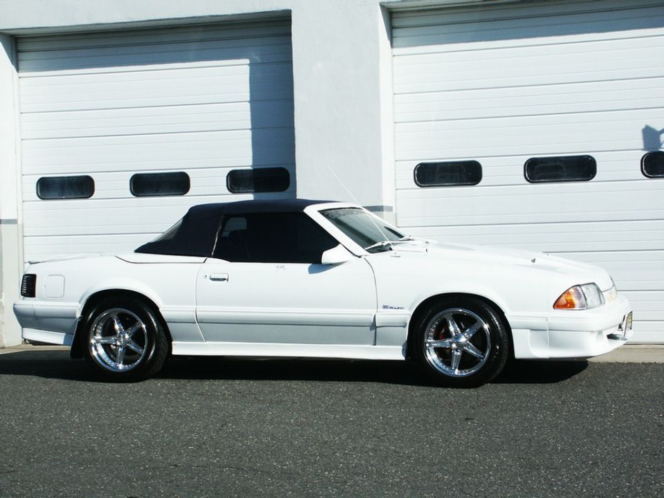 White convertible with black top parked in front of a garage door