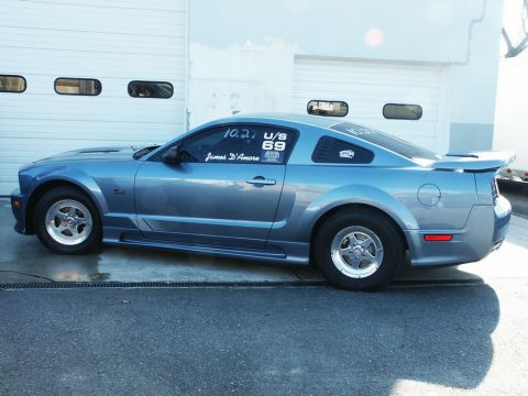 2001 Mercury Grand Marquis - A blue coupe, likely a Ford Mustang, is parked outside a garage with racing slicks on its wheels.