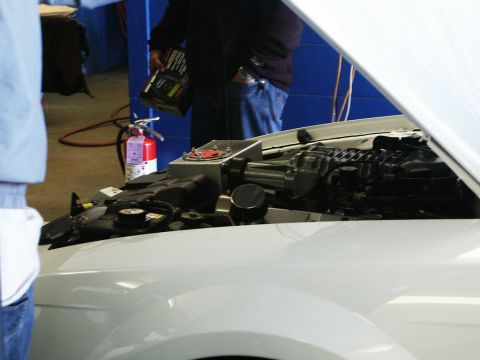 2001 Mercury Grand Marquis - Mechanic working on a car's engine bay, with a fire extinguisher nearby.