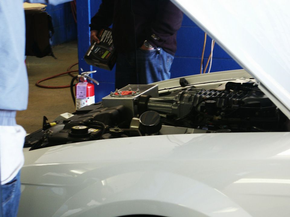 White car's engine bay, showing a supercharger and parts. Fire extinguisher visible