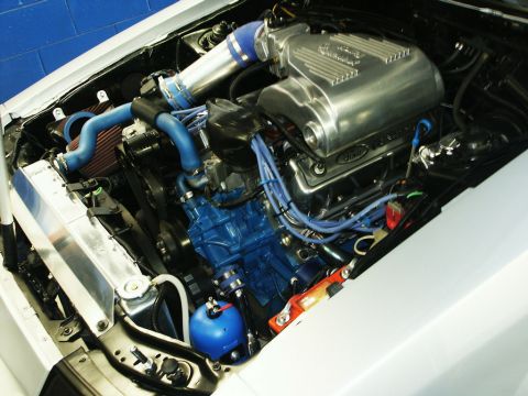 2001 Mercury Grand Marquis - Close-up view of a modified V8 engine bay an aluminum intake manifold, blue hoses, and an aftermarket radiator. The Supermotors.net logo is…