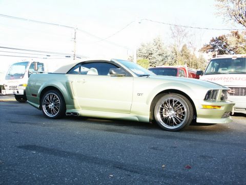 2001 Mercury Grand Marquis - A light green Ford Mustang GT convertible is parked on a street, with other vehicles visible in the background.