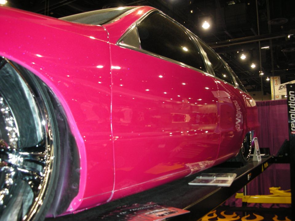 Close-up of pink custom car body panel with chrome wheel and Revolution banner