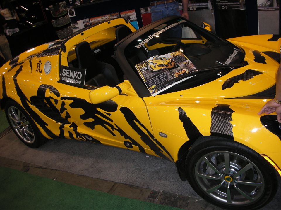 Yellow Lotus Elise roadster with black tribal graphics and SENKO decal at show